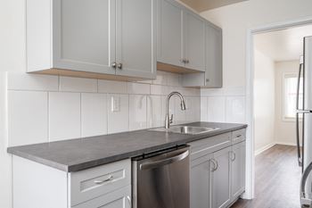 a kitchen with white cabinets and gray countertops